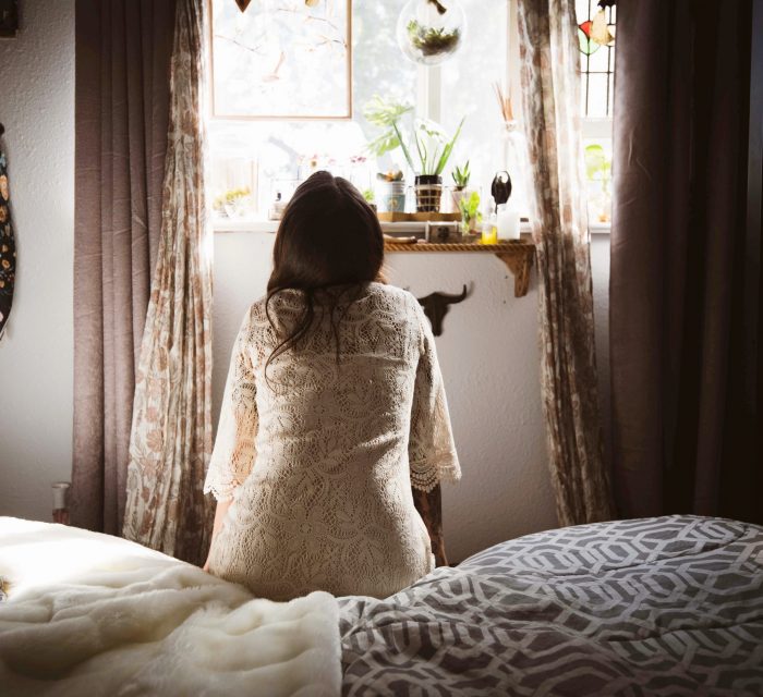 Schlechtes gewissen loswerden: Mädchen von hinten auf einem Bett sitzend