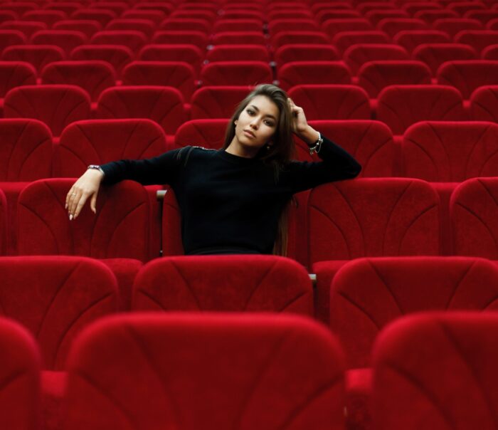 schwarzgekleidetes Mädchen in roten Kino-Plüschsesseln